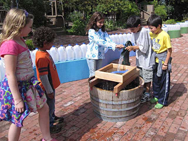 Children playing with hand water pump