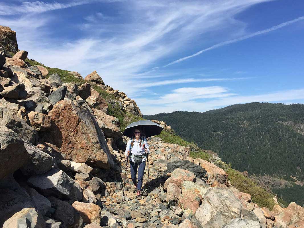 Walking along PCT with trekking umbrella